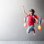 Happy child playing with toy jetpack. Kid pilot having fun at home. Success, innovation and leader concept